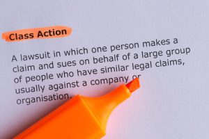 A piece of paper that says: Class Action | A lawsuit in which one person makes a claim and sues on behalf of a large group of people who have similar legal claims, usually against a company or organisation.
